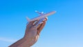 Ban of flights is suspended. Airplane model in hand against clear blue sky