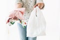 Ban single use plastic. Zero Waste shopping concept. Woman holding in one hand groceries in reusable eco bag and in other