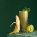 Banana apple and mint smoothie. Dietary vitamin cocktail for detox. Glass with mixed fruits on green background. Healthy Royalty Free Stock Photo