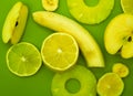 Banana, apple, pineapple and lemon on green background - top view