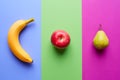 Banana on blue, apple on green and pear on pink, from above Royalty Free Stock Photo