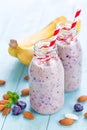 Banana and blueberry diet smoothie with yogurt or milk, almonds and fresh berries in glass bottles