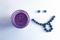 banana and blueberry smoothie in a glass cup with a smiling face of blueberries Royalty Free Stock Photo