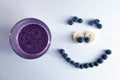 banana and blueberry smoothie in a glass cup with a smiling face of blueberries Royalty Free Stock Photo