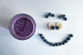 banana and blueberry smoothie in a glass cup with a smiling face of blueberries Royalty Free Stock Photo