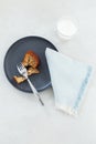 Banana bread in black dish, with glass of milk and cotton serviette on pale background