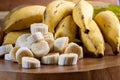 Banana bunch, sliced bananas in bowl and on wooden board