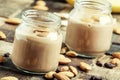 Banana-chocolate smoothie with almonds in glass jars, vintage wooden background, selective focus