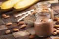 Banana-chocolate smoothie with almonds in glass jars, vintage wooden background, selective focus