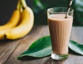 Banana-chocolate smoothie with cocoa, in a tall glass, on a wooden table. Healthy drink, vegetarian