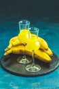 Banana flavoured liqueurs, which French call creme de banana, in grappas wineglass on dark blue concrete surface