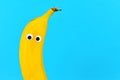 Banana fruit with funny googly eyes on bright bue background with copy space