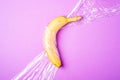 Banana fruit wrapped in stretch wrap plastic on pink background, minimalistic creative layout