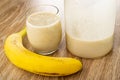 Banana, glass of cocktail, glass with blend from banana and milk on wooden table