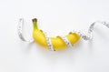 A banana with a measuring tape wrapped around a white background Royalty Free Stock Photo