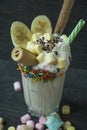 Banana milkshake with ice cream and whipped cream, marshmallows, cookies, waffles, served in a glass cup decorated with Royalty Free Stock Photo