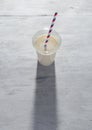 Banana milkshake in plastic cup on white wooden background Royalty Free Stock Photo