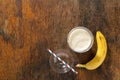 Banana milkshake in plastic cup on wooden background Royalty Free Stock Photo
