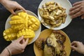 Banana pancakes, fried bananas, yellow mango and people hands. Yummy dessert, close up, top view Royalty Free Stock Photo