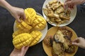 Banana pancakes, fried bananas, yellow mango and people hands. Yummy dessert, close up, top view Royalty Free Stock Photo