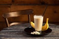 Banana shake with banana slices on wooden background