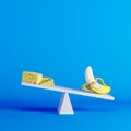 Banana sitting on seesaw with cheese on opposite end on blue background