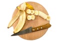 Banana slices, peel and knife on a wooden board on a white background. Close-up. View from above. Royalty Free Stock Photo