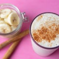 Banana smothie or milkshake with cinnamon on pink background