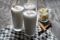 Banana smothie or milkshake with cinnamon on wood background