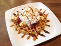 Banana split with whip cream, ice cream, strawberry jam and syrup on top of waffle