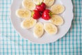 Banana and strawberries on a white plate and a colorful napkin Royalty Free Stock Photo