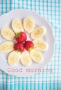 Banana and strawberries on a white plate inscription good morning