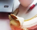 Banana on table with computer and red pen Royalty Free Stock Photo