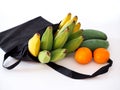 Bananas in black cloth bags with citrus orange fruits isolated on white background Royalty Free Stock Photo