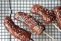 Bananas in chocolate with a multicolored powder lying on a black baking tray