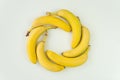 Bananas folded in the shape of a circle lie on a white background of the table. top view, above view Royalty Free Stock Photo