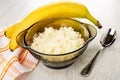 Bananas on napkin, cooked rice porridge in brown bowl, spoon on wooden table Royalty Free Stock Photo