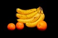 bananas orange and two tangerines on a black background Royalty Free Stock Photo