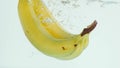 Bananas plunging into water on white background in slow motion