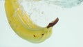 Bananas plunging into water on white background in slow motion