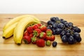 Bananas, strawberries and blue grapes on the table. Royalty Free Stock Photo