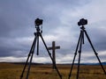 Nikon D800 and D300 cameras on Manfrotto tripods in front of wooden cross. Royalty Free Stock Photo