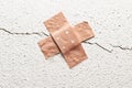 Band-aid plaster in cross shape on a crack in the wall, concept Royalty Free Stock Photo