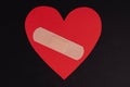 Band-aid for wounds on a red heart on a black background. Heart wounds. Royalty Free Stock Photo