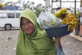 Street saleswoman in Muslim clothing offers roasted peanuts and boiled corn