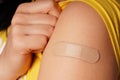 Bandage on young woman`s arm after scratch on skin or injection for vaccine. A medical patch or plaster on a female shoulder afte