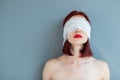 Bandaged eyes of young woman, conceptual indoor portrait. Person who doesn't notice anything.