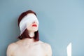 Bandaged eyes of young woman, conceptual indoor portrait. Person who doesn't notice anything.