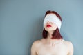 Bandaged eyes of young woman, conceptual indoor portrait. Person who doesn't notice anything.