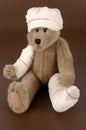 Bandaged teddy bear on brown background Royalty Free Stock Photo
